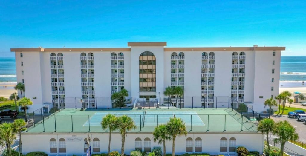 un gran edificio blanco con palmeras frente a la playa en Beach Oasis 601 Gorgeous Ocean front Ocean view for 10 sleeps up to 14 en Daytona Beach