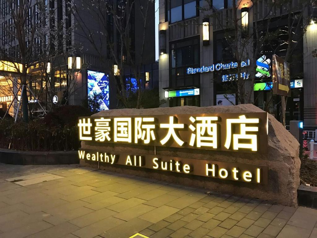 ein Schild für ein Hotel in einer Stadt in der Nacht in der Unterkunft Wealthy All Suite Hotel Suzhou in Suzhou