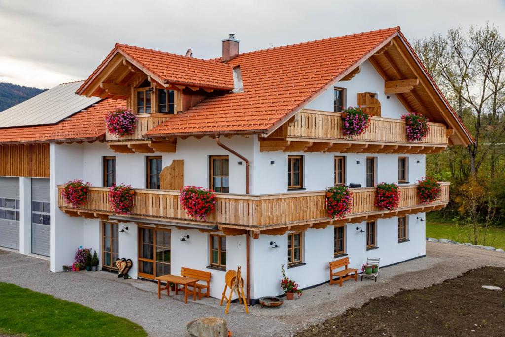 ein weißes Haus mit orangefarbenem Dach in der Unterkunft Ferienwohnungen zum Nigglhof in Wackersberg