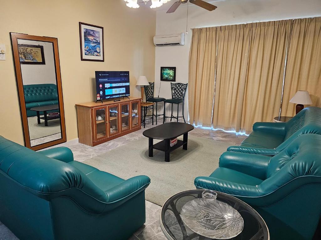 un salon avec des canapés bleus et une télévision dans l'établissement Senorita Sea View At Ocean View Resort, à Port Dickson