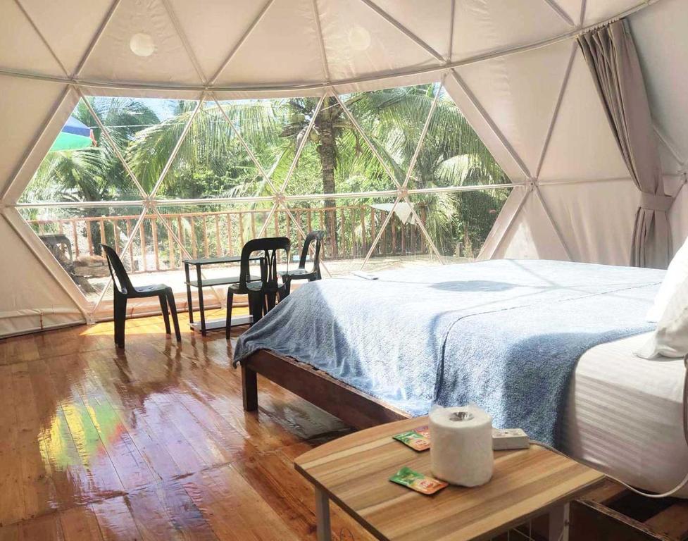 Una habitación con una cama y una mesa en una tienda de campaña en Eco Glamping Treehouses Closest Resort To All Tourist Attractions, en Balilihan