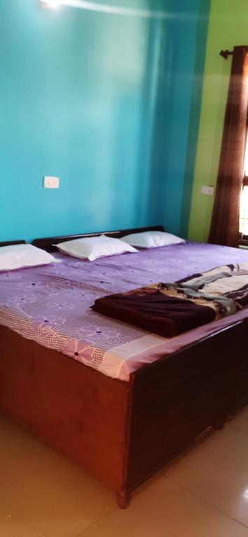 a bed with a purple comforter on top of it at Hotel aasra guest house in Bharwain