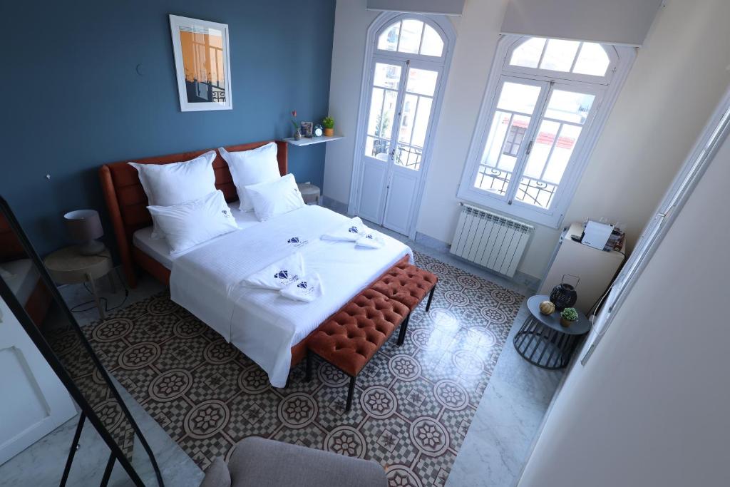 a bedroom with a bed with a table and two windows at THE GEM BOUTIQUE HOTEL in Beirut