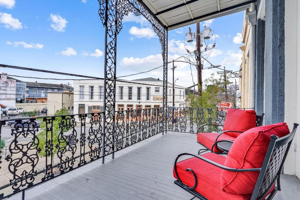 einen Balkon mit roten Stühlen und Blick auf ein Gebäude in der Unterkunft Unique Lower Garden District Condo W Balcony! in New Orleans