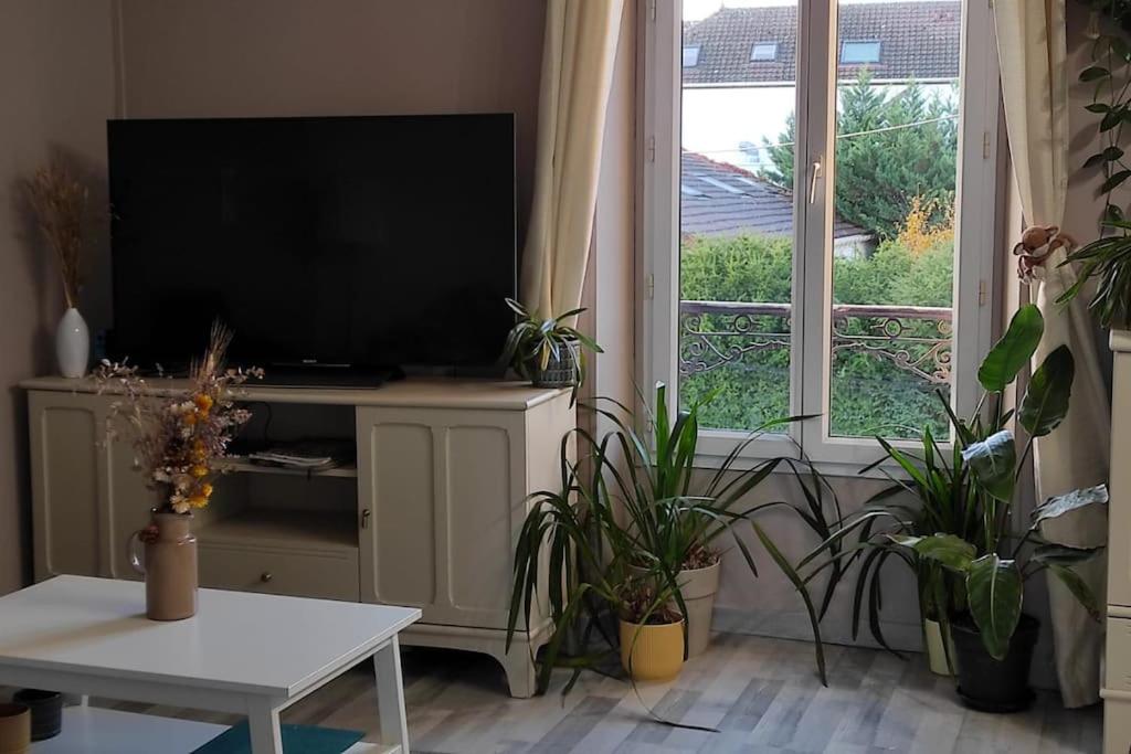 a living room with a flat screen tv and plants at Calme à 3 min de la Gare de Melun in Melun