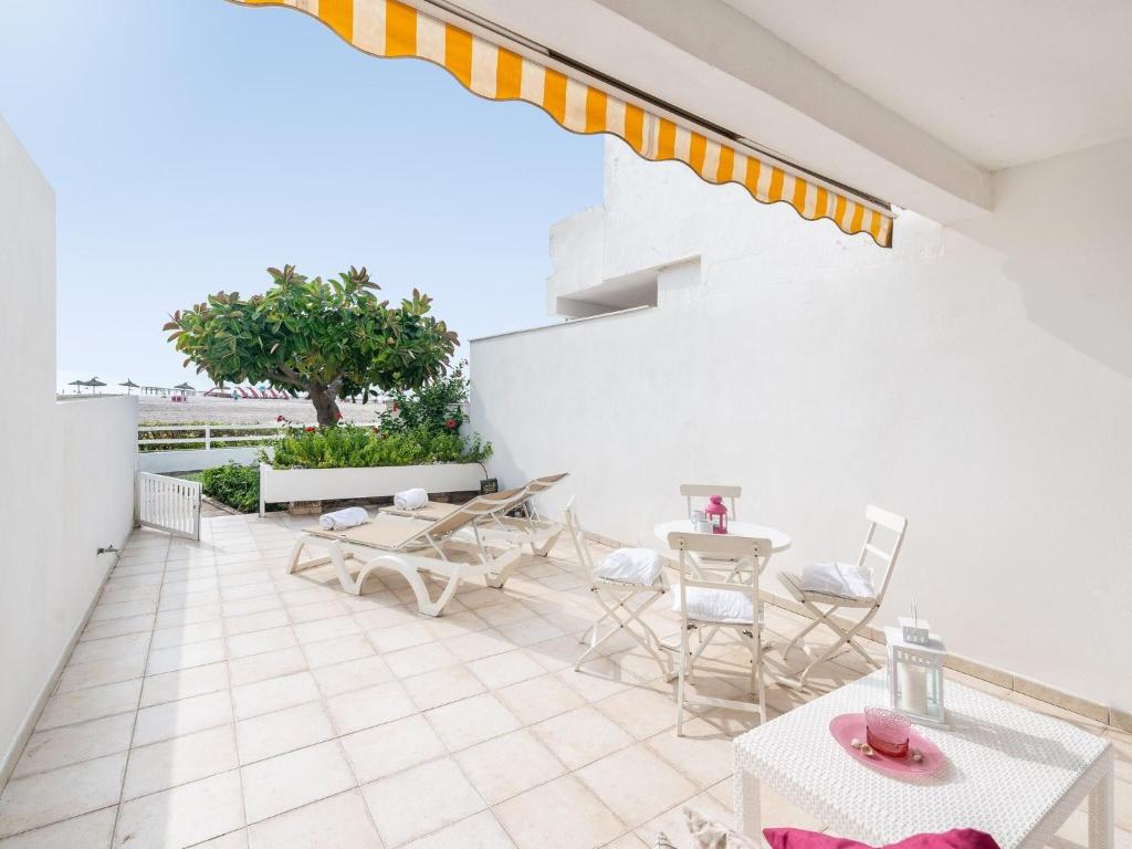 een patio met tafels en stoelen aan een witte muur bij Apartamento 23 Edificio Canopus Apartment In Port D alc dia Free Wifi in Port d'Alcudia