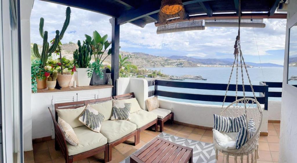 a porch with chairs and a swing and a view of the water at Marina Sunrise in La Herradura