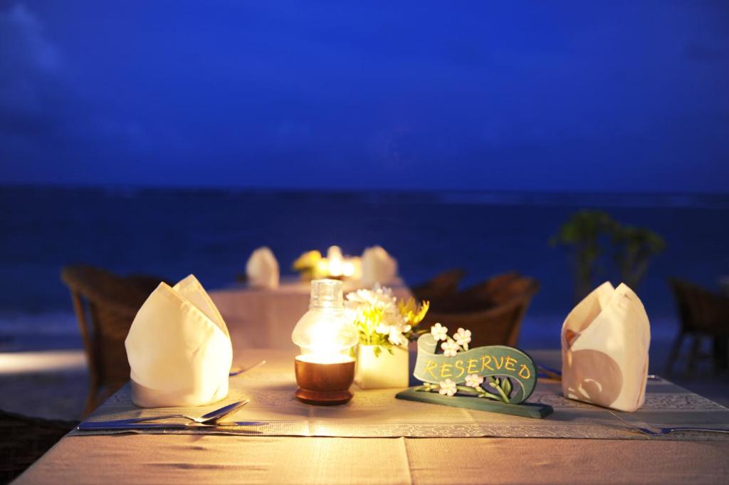 a table with a candle and flowers on it at Montien House - SHA Plus in Chaweng