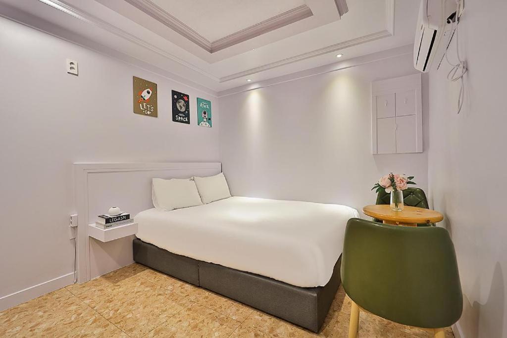 a bedroom with a white bed and a green chair at Gwanganri A Hotel in Busan