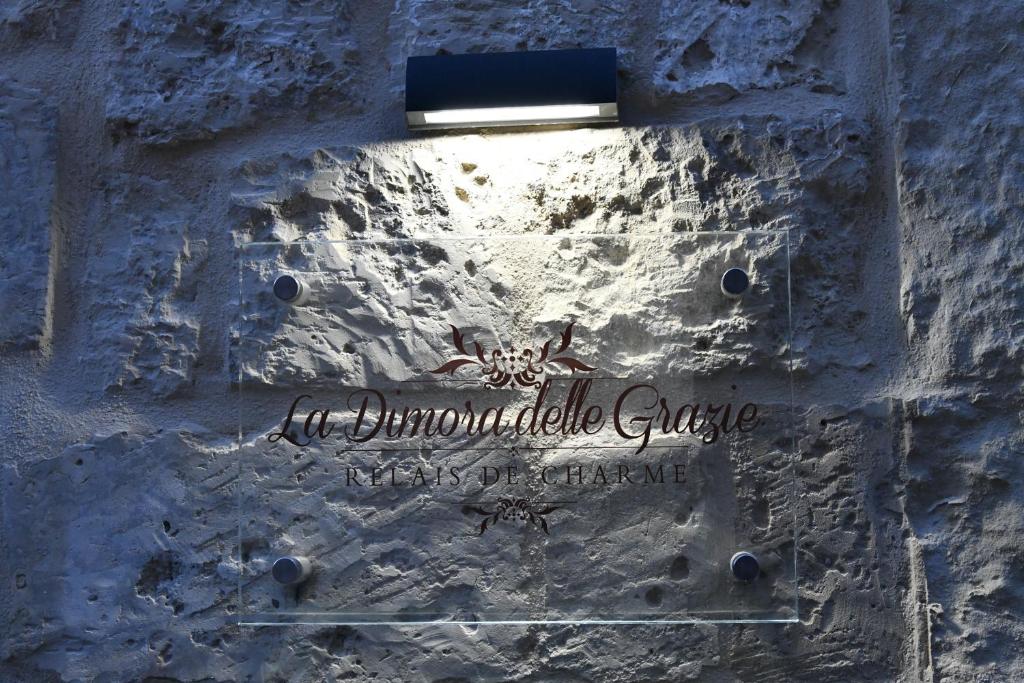 um sinal no lado de uma parede de pedra com uma luz em La Dimora delle Grazie em San Cesario di Lecce