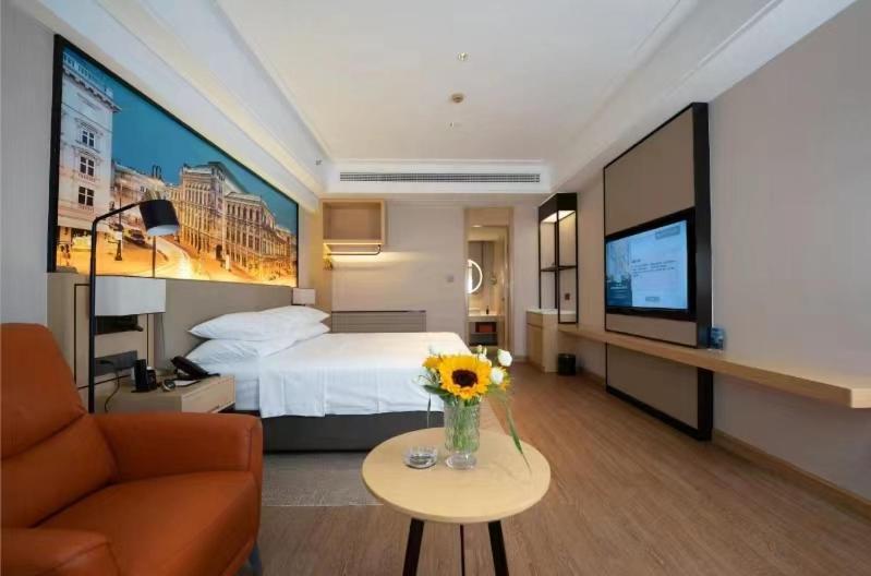 a hotel room with a bed and a vase of flowers at Vienna International Hotel - Changsha Yuelu Lugu Hi-Tech Zone in Changsha