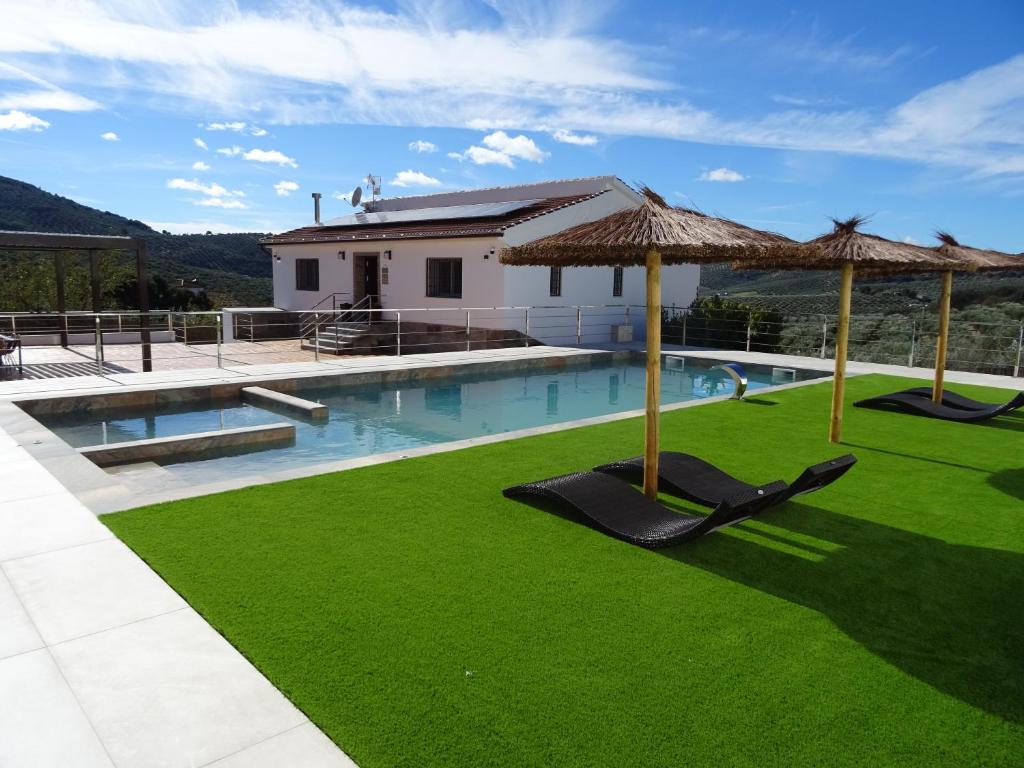 - une piscine avec 2 chaises longues et un parasol dans l'établissement La Villa de Alba - Casa Rural en Montefrío, à Montefrío