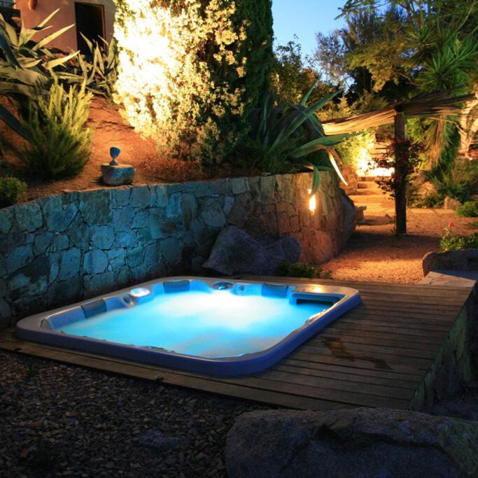 a jacuzzi tub sitting on a wooden deck at Chambre cosy Aphrodite avec accès a la piscine et au jacuzzi in Porto-Vecchio