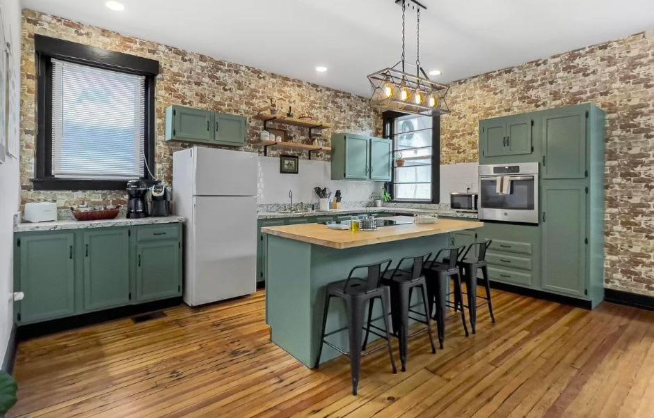una cocina con armarios verdes y una isla con taburetes. en Cozy Home near Downtown - Close to Nulu - Sleeps 6, en Louisville