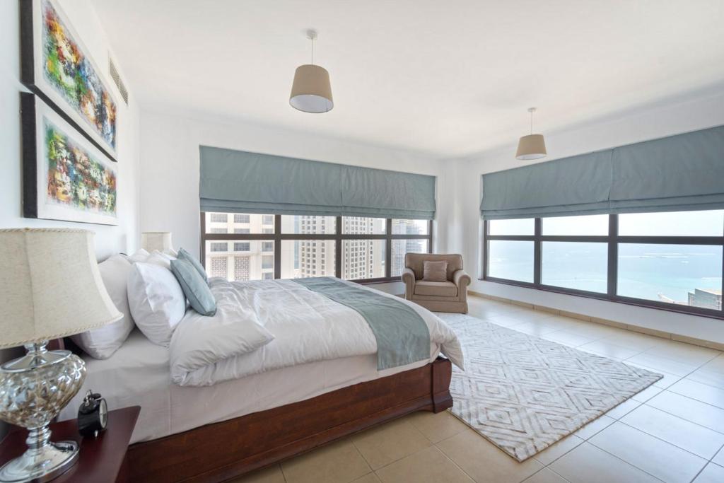 een slaapkamer met een groot bed en grote ramen bij Stunning Marina & Sea View 4 Bedroom Apartment, Murjan 6 Jumeriah Beach in Dubai