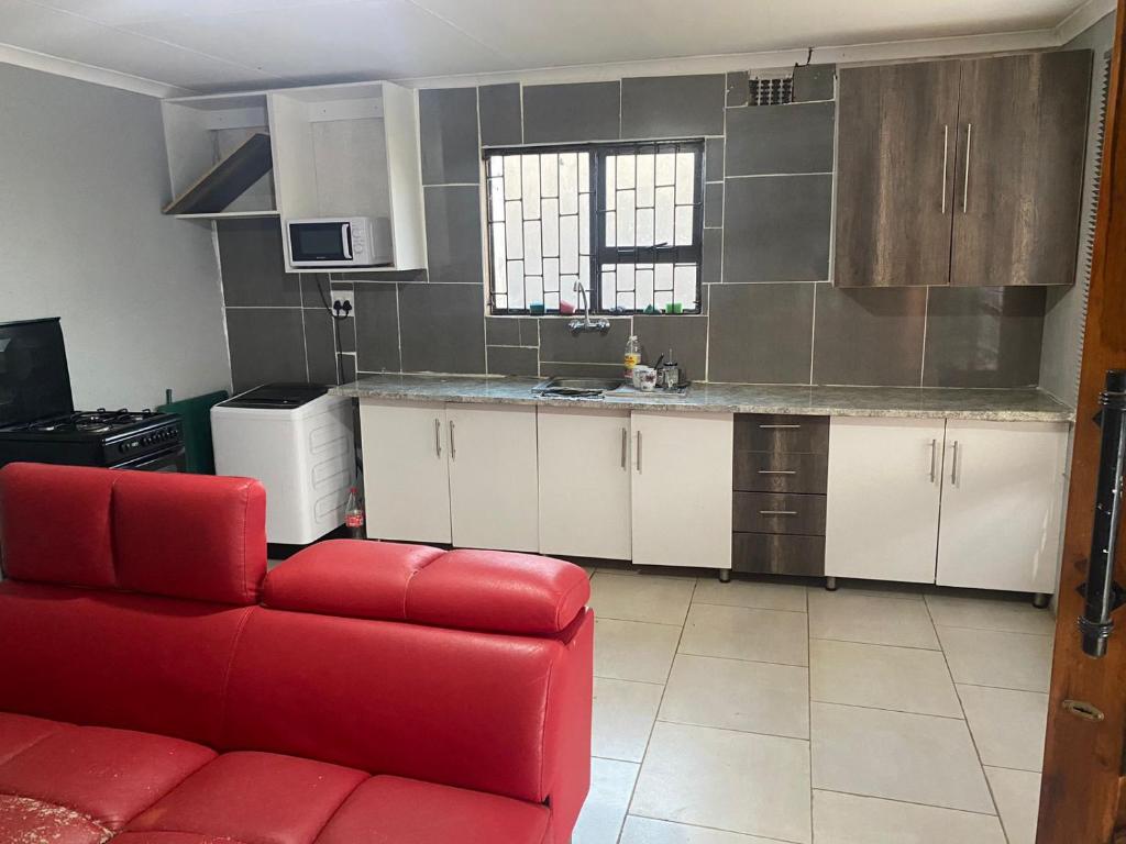 a living room with a red couch in a kitchen at Airportview heights 