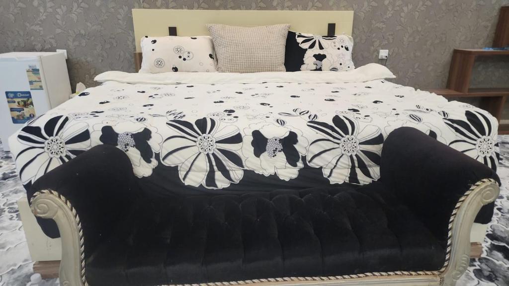 a bed with a black and white comforter with flowers at اطلالة الوادي غرفة ساحرة في صامطة in Şāmitah