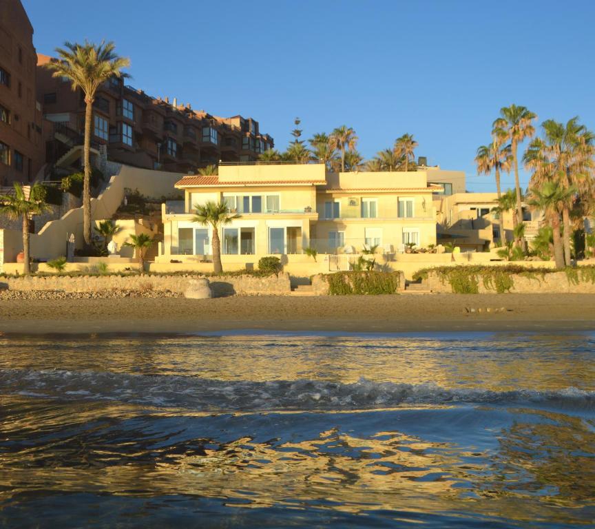 una casa en la playa con palmeras y agua en Extraordinario apartamento a pie de playa en Chalet Roquetes en Alicante