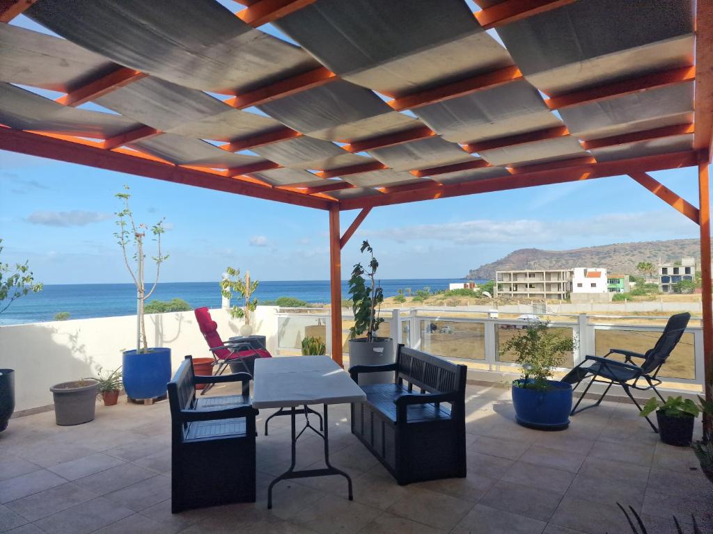 een patio met een tafel en stoelen en de oceaan bij Kaps Home - Tarrafal in Tarrafal