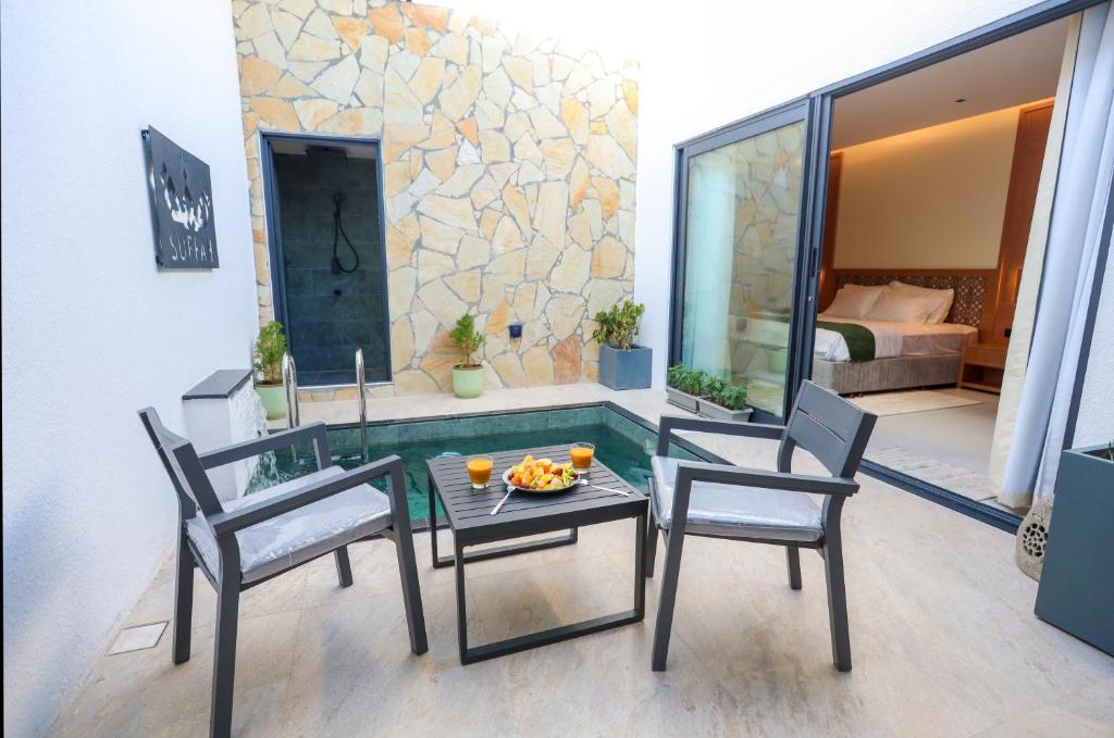 eine Terrasse mit einem Tisch, 2 Stühlen und einem Pool in der Unterkunft Suffah Chalet in Nizwa