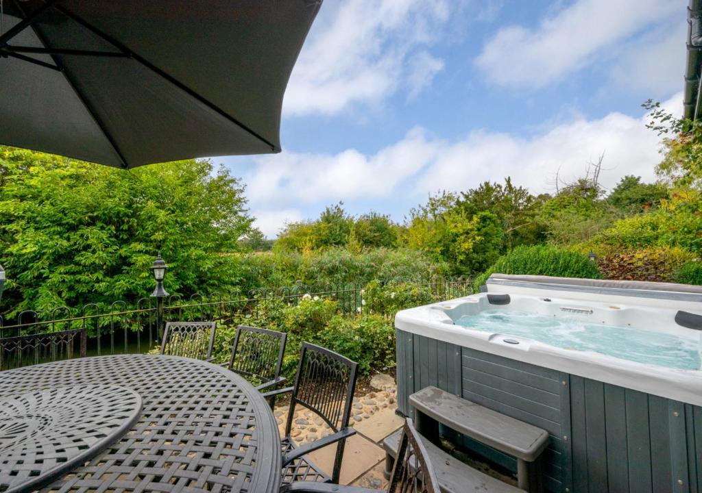 a table with an umbrella next to a hot tub at Tithe Barn at Wattisham Hall in Wattisham