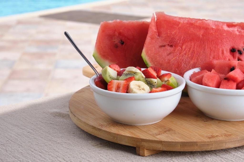 two bowls of fruit sitting on a wooden board at Amorgion Village in Katapola