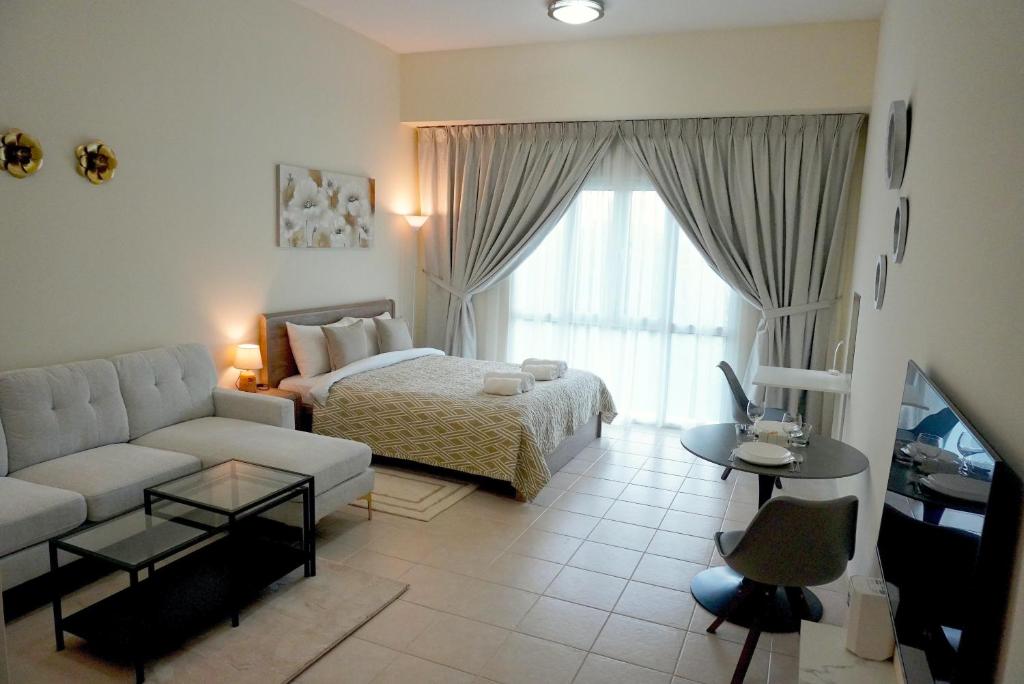 a living room with a white couch and a bed at Brand New Cozy Studio Apatrtment in Dubai