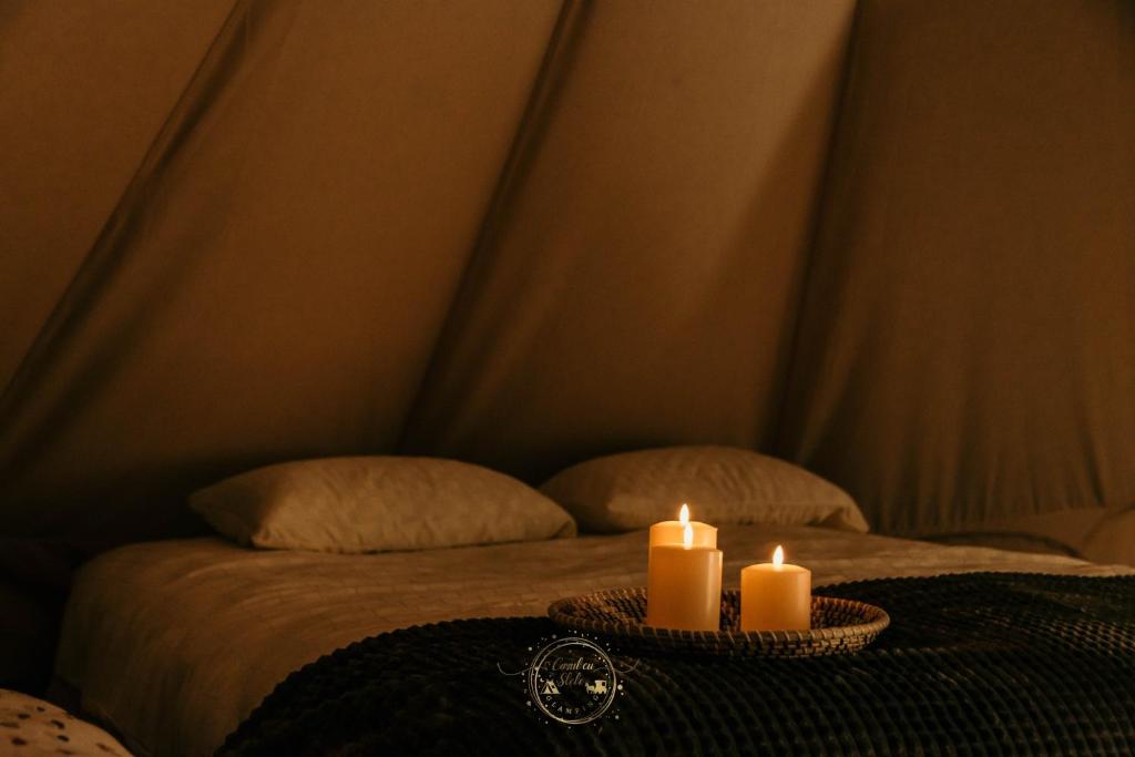 una mesa con dos velas en la parte superior de una cama en Carul cu Stele-Glamping, 
