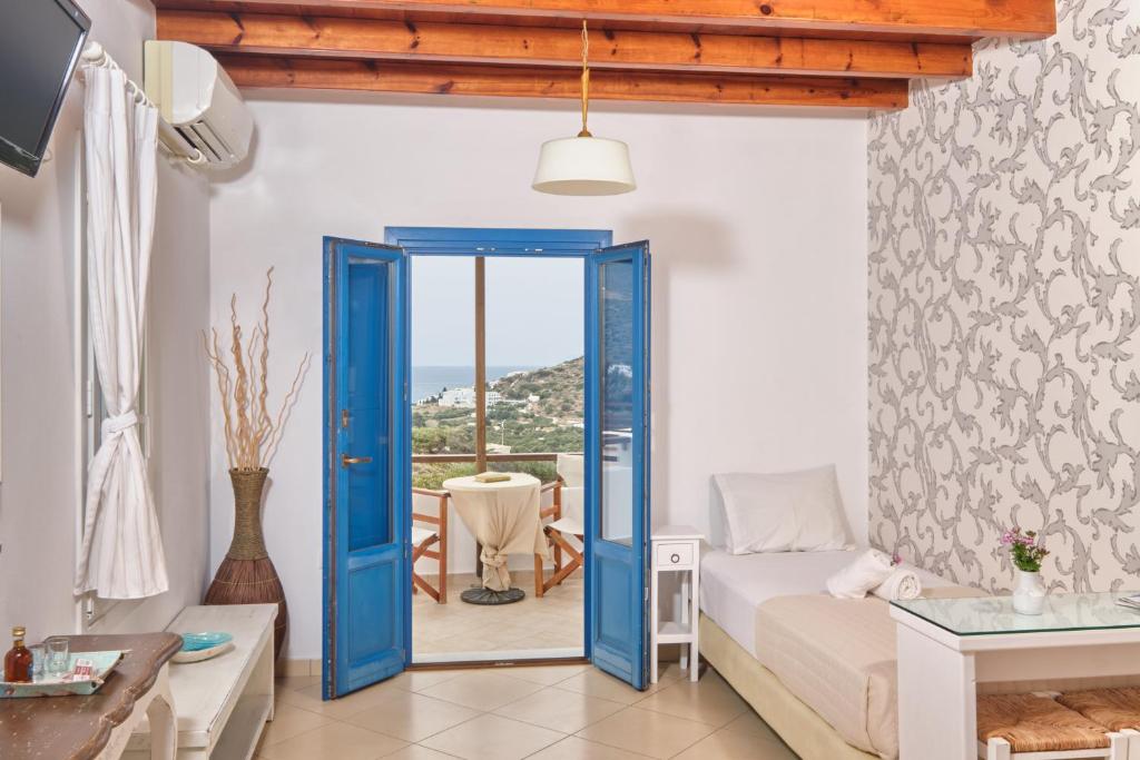 a bedroom with a blue door leading to a balcony at Amorgion Village in Katapola