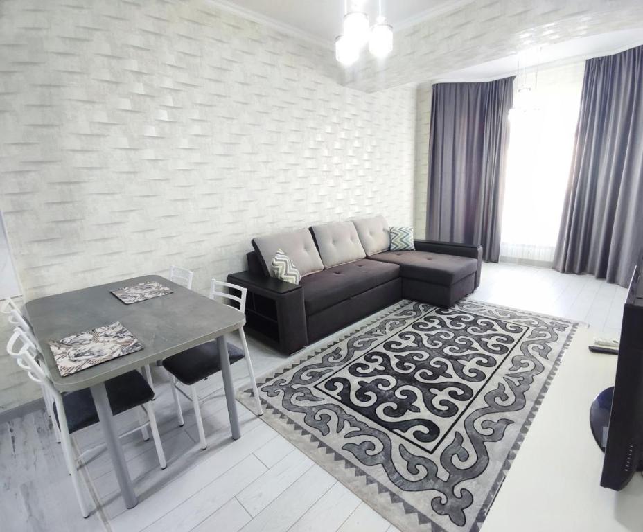 ein Wohnzimmer mit einem Sofa und einem Tisch in der Unterkunft Комфортная двухкомнатная квартира in Bischkek