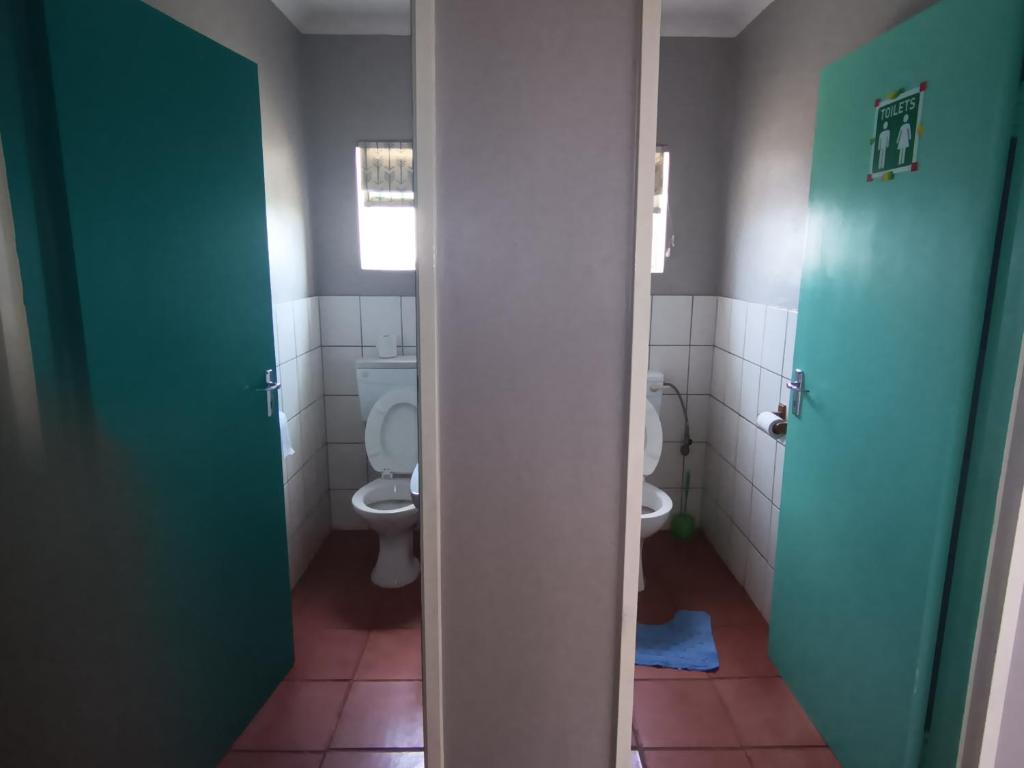 baño con 2 aseos y puertas verdes en Prime Guest Inn, en Benoni