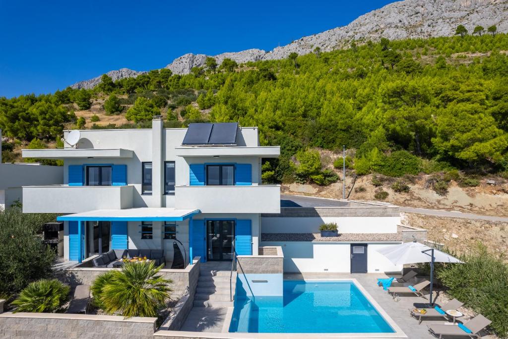 a house with a swimming pool and a mountain at Villa Allegra with 32msq heated pool, 300m far from sandy beaches, open sea view in Omiš