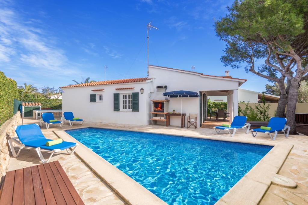 une villa avec une piscine et des chaises bleues dans l'établissement Villa Can Bolduc by Villa Plus, à Cala en Blanes