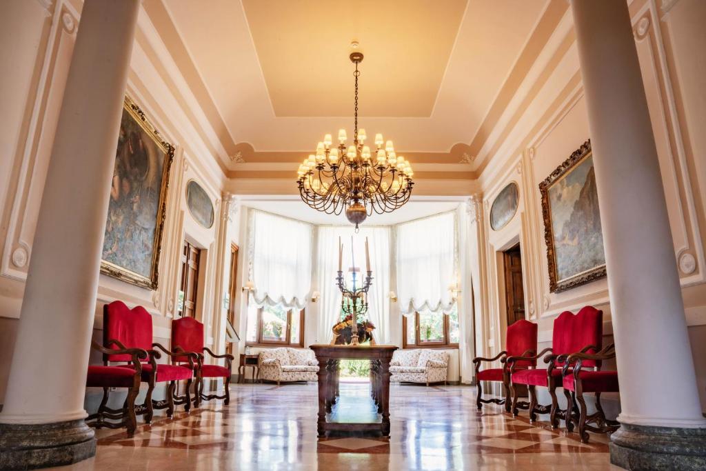 ノーヴィ・リーグレにあるルレ ヴィラ ポメラの赤い椅子とシャンデリアが備わる広い客室です。