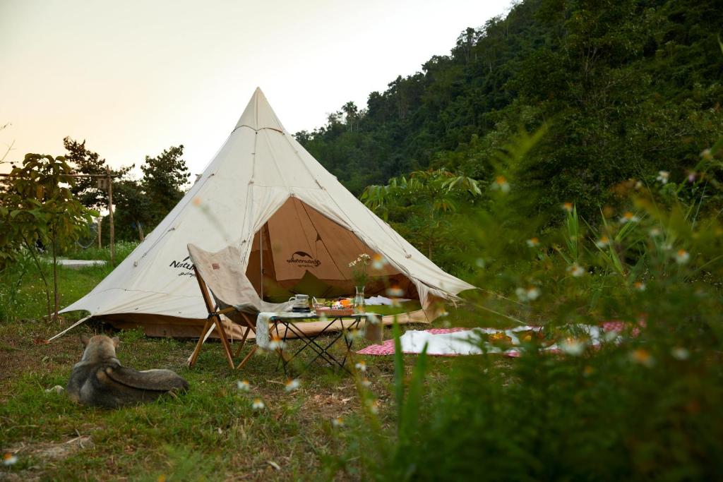 a tent with a table and a chair in the grass at The BanBa Jungle Lodge in Làng Hoa (2)