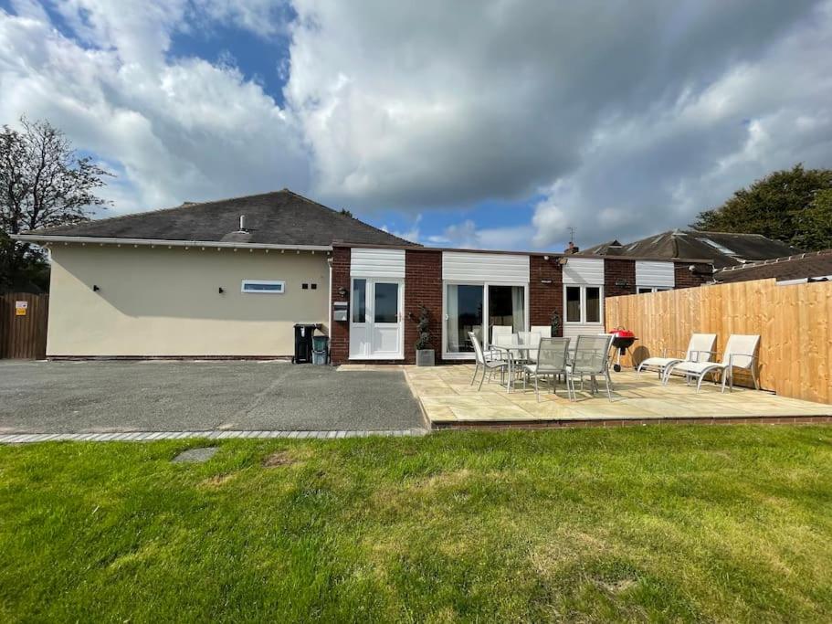 a house with a patio with chairs and a fence at The Ridge Bungalow, at the highest point in the Heart of Cheshire in Frodsham