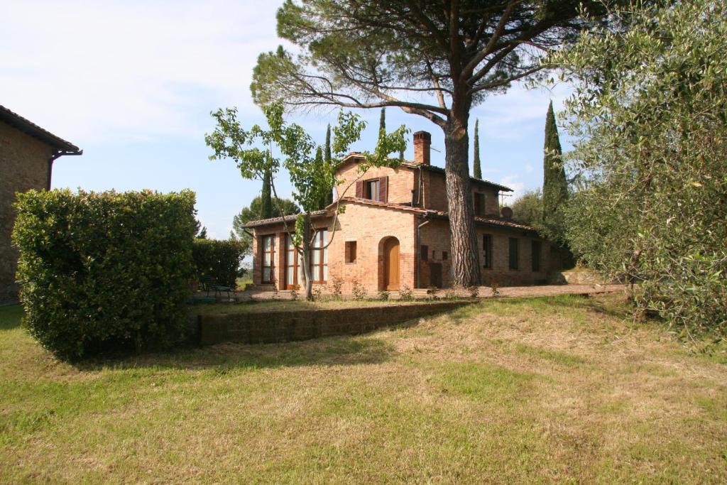 una vecchia casa con un albero in un campo di Colombina a Siena