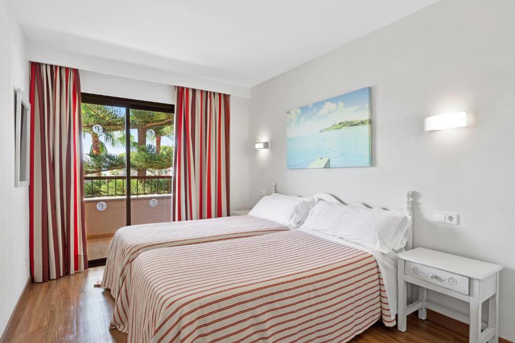 a white bedroom with a bed and a window at Apartamentos Pabisa Orlando in Playa de Palma
