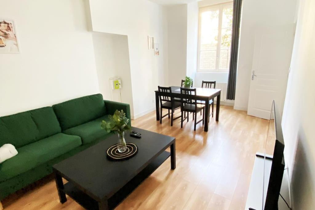 ein Wohnzimmer mit einer grünen Couch und einem Tisch in der Unterkunft Bel appartement neuf et facile d'accès in Orléans
