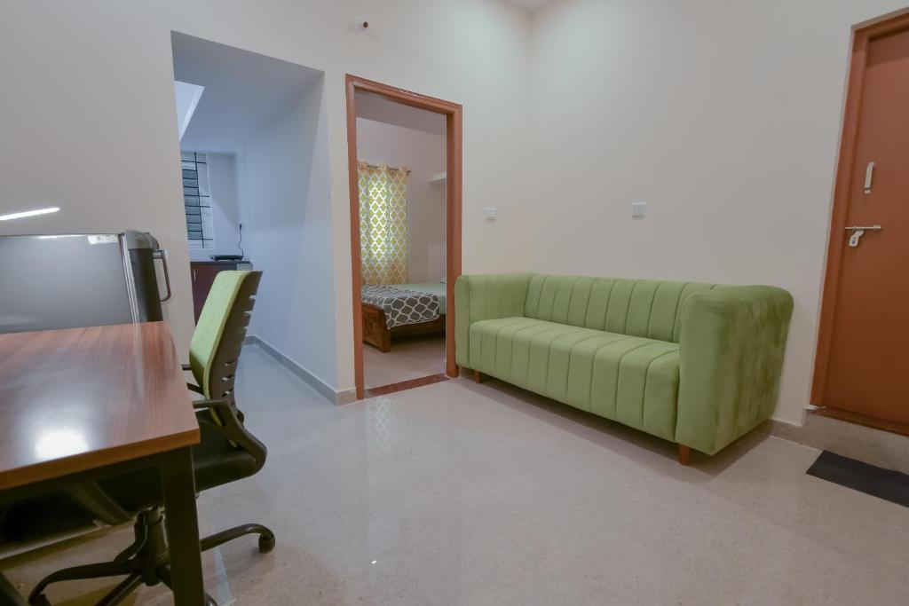 a living room with a green couch and a desk at HomeSlice Manzil - 1BHK in HSR in Bangalore