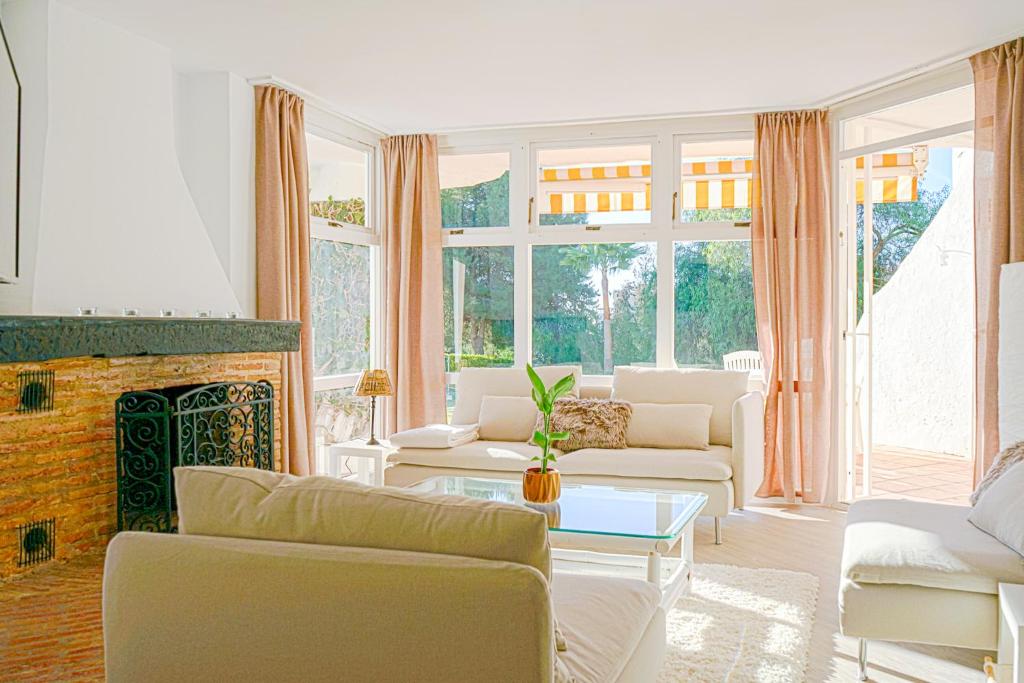 uma sala de estar com mobiliário branco e uma lareira em Lovely two bedroom apartment Calahonda - 475 meter from the beach em Cabopino