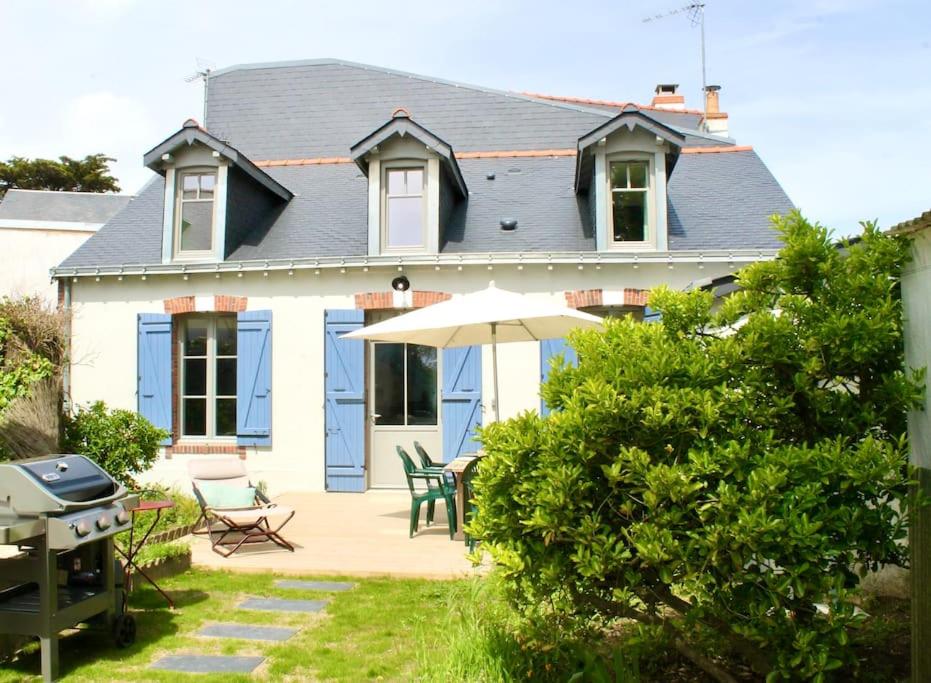 uma casa com um pátio com um guarda-sol e um grelhador em Face Mer Villa Le Petit Breton em Pornichet