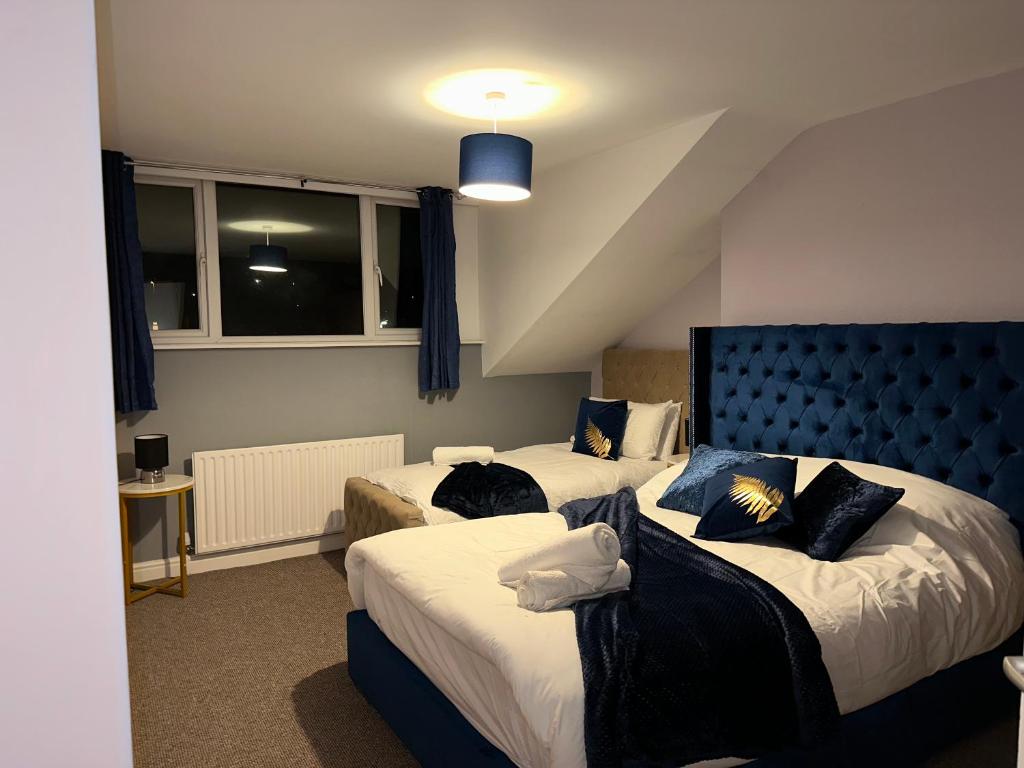 a bedroom with two beds and a blue headboard at Charming 2-Bed Apartment in the Heart of Leeds in Leeds