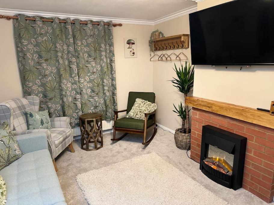 a living room with a fireplace and a flat screen tv at Vine Cottage- Stunning newly renovated cottage 
