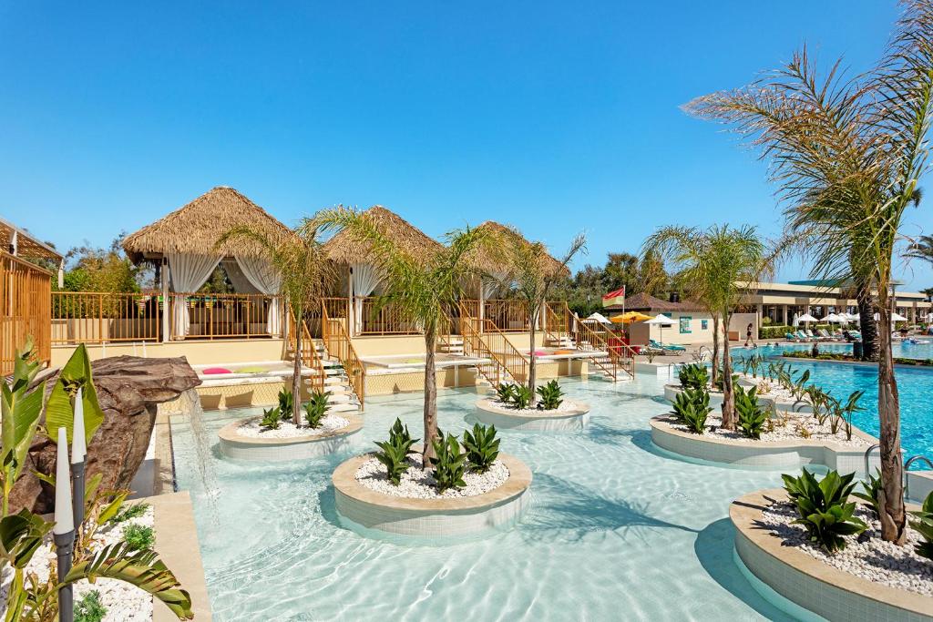 a resort with a pool with tables and palm trees at Liberty Hotels Lara in Lara