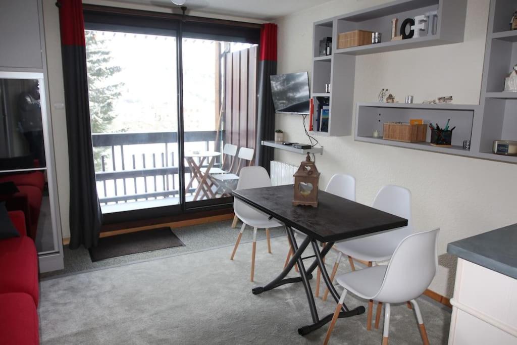 a living room with a table and chairs and a balcony at Appartement aux pieds des pistes chez Seb et Isa in Saint-François-Longchamp