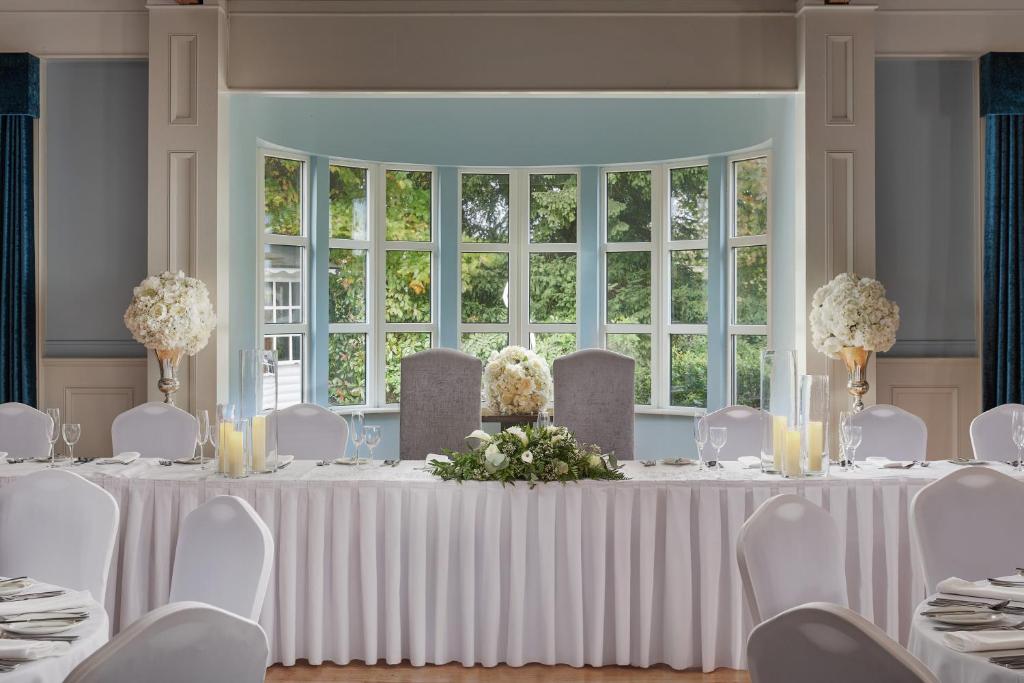 a white table with white chairs and a large window at Springfield Hotel in Leixlip