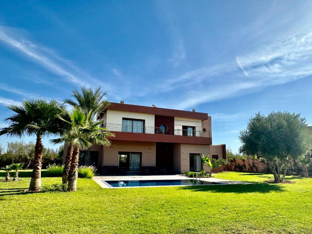 a house with a swimming pool and palm trees at Mandar Atlas in Marrakech