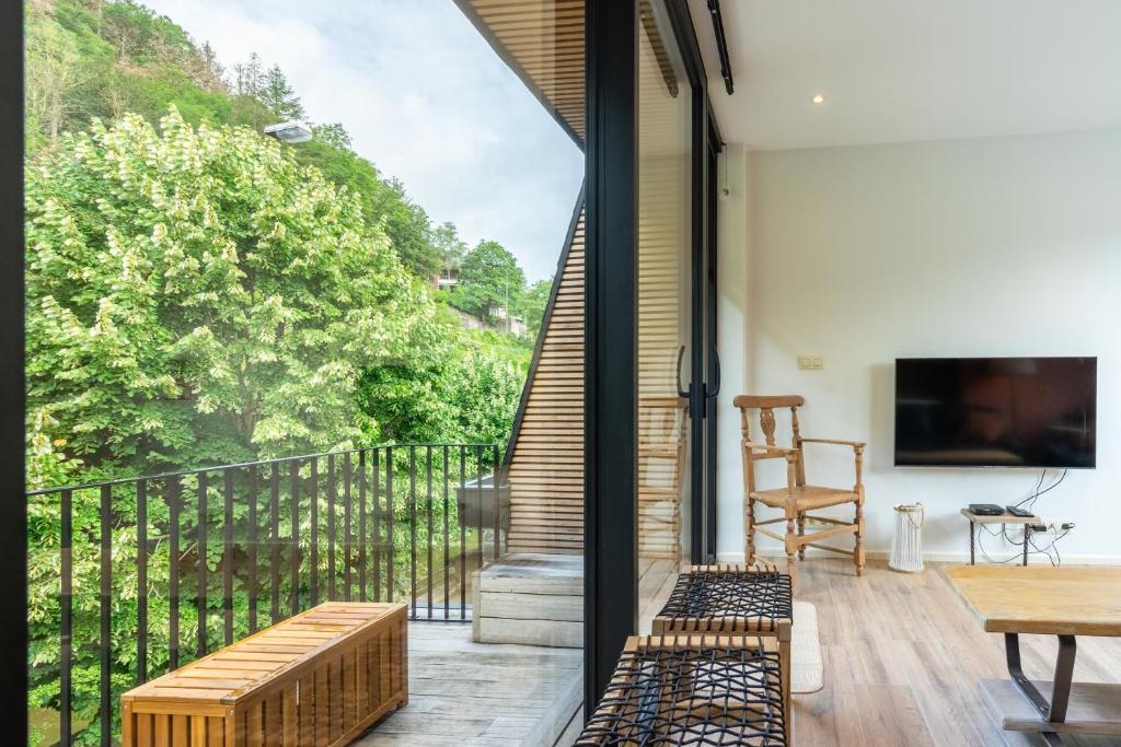 een kamer met een balkon met banken en een televisie bij Li Rotche in La-Roche-en-Ardenne