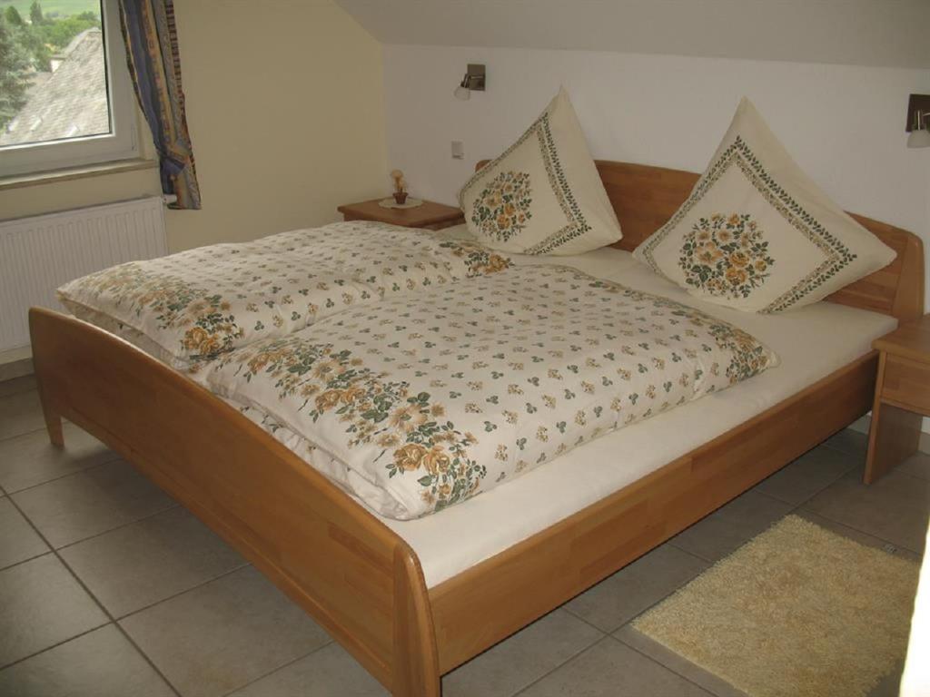ein Bett mit einem Holzrahmen und Kissen darauf in der Unterkunft Haus Klara in Detzem